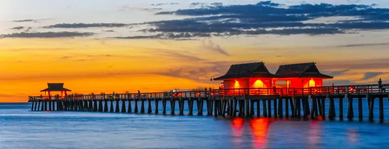 Naples Pier stretching into the Gulf after sunset, its lights reflected in the water