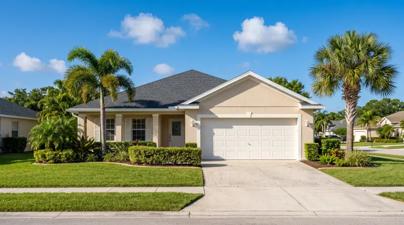Single-story Florida home with a white garage door, palm trees and a concrete driveway